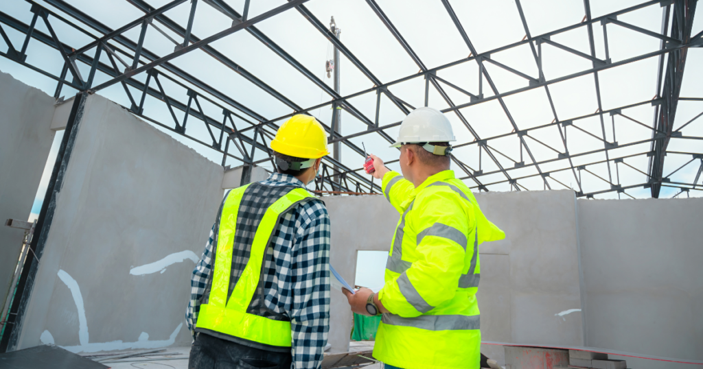 Two contractors in hats reviewing the conformance of a structure during a structural inspection